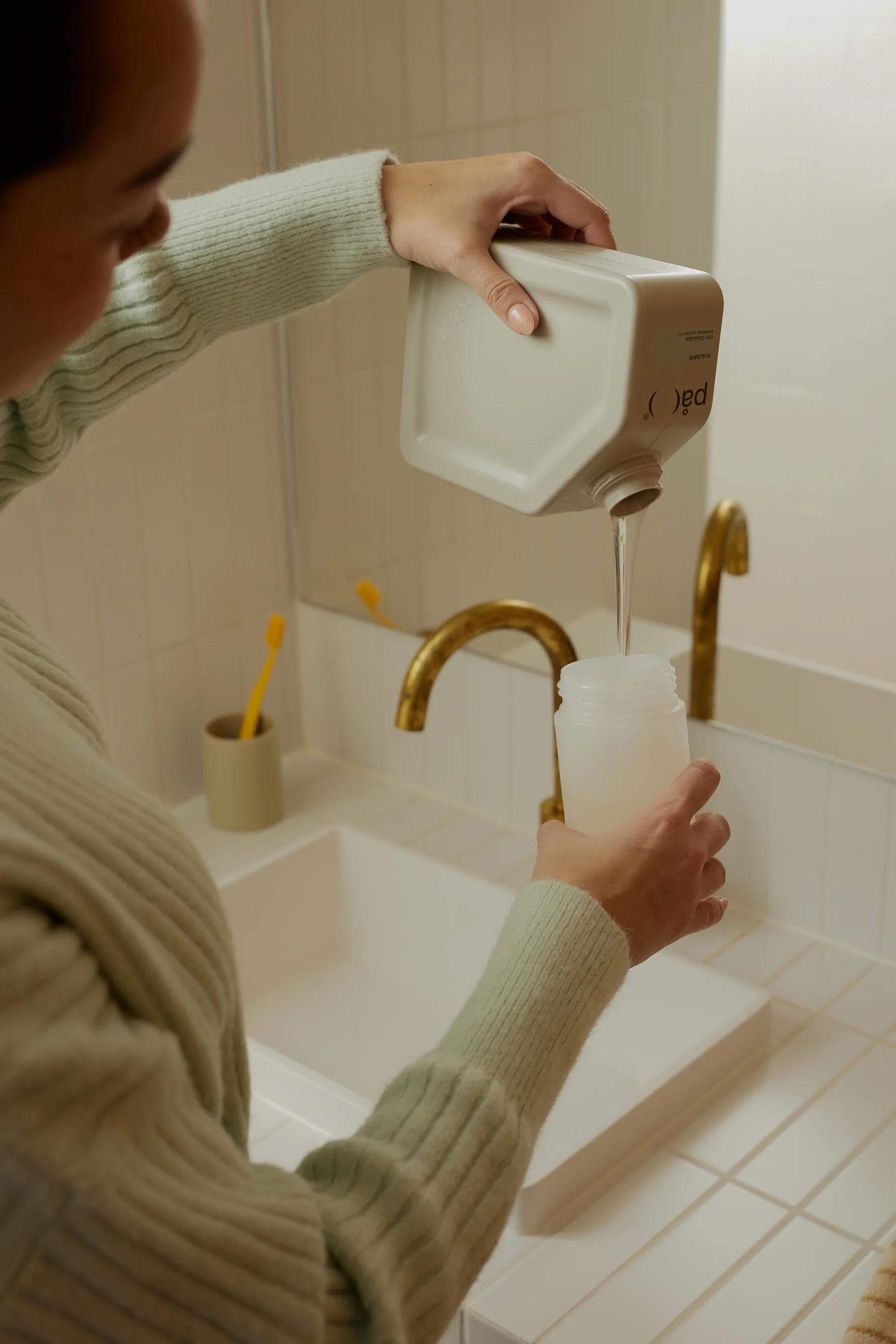 Woman pouring soap from På(fyll) container into dispenser